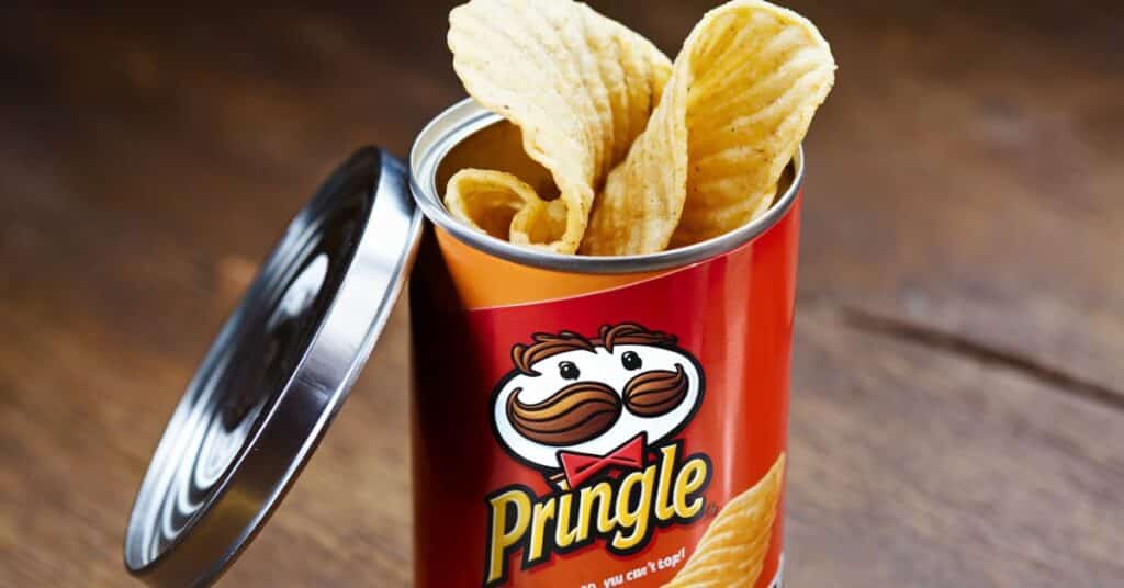 A photo of a Pringle can with the lid removed, revealing the crispy  golden brown potato chips with a  slight curve.