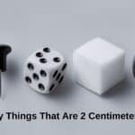 Collage of everyday items measuring 2 centimeters, thumbtack, dice, sugar cubes, and a rubber band.