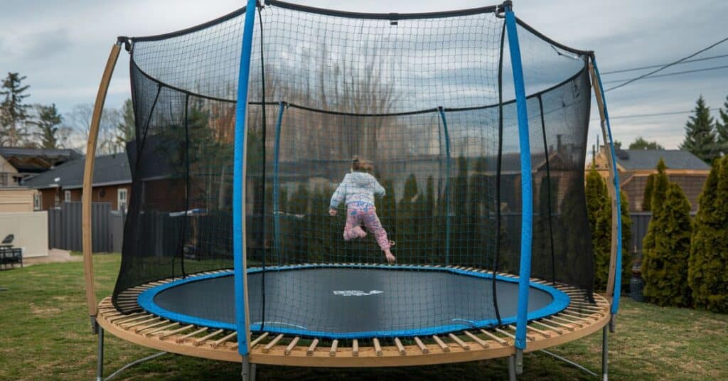 An image of a girl jumping on the trampoline in the backyard, illustrating the fun associated with 5 meters objects.