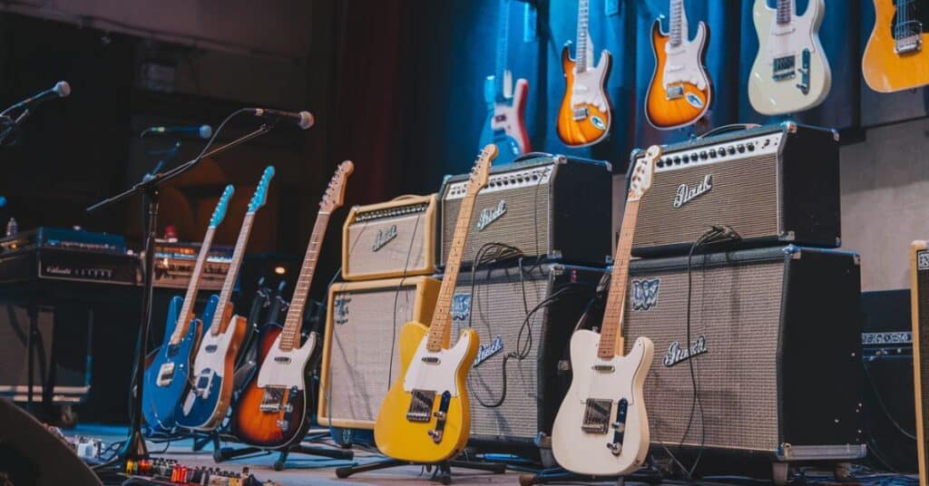 Few elecrtic guitars are placed on stage with mics and speakers