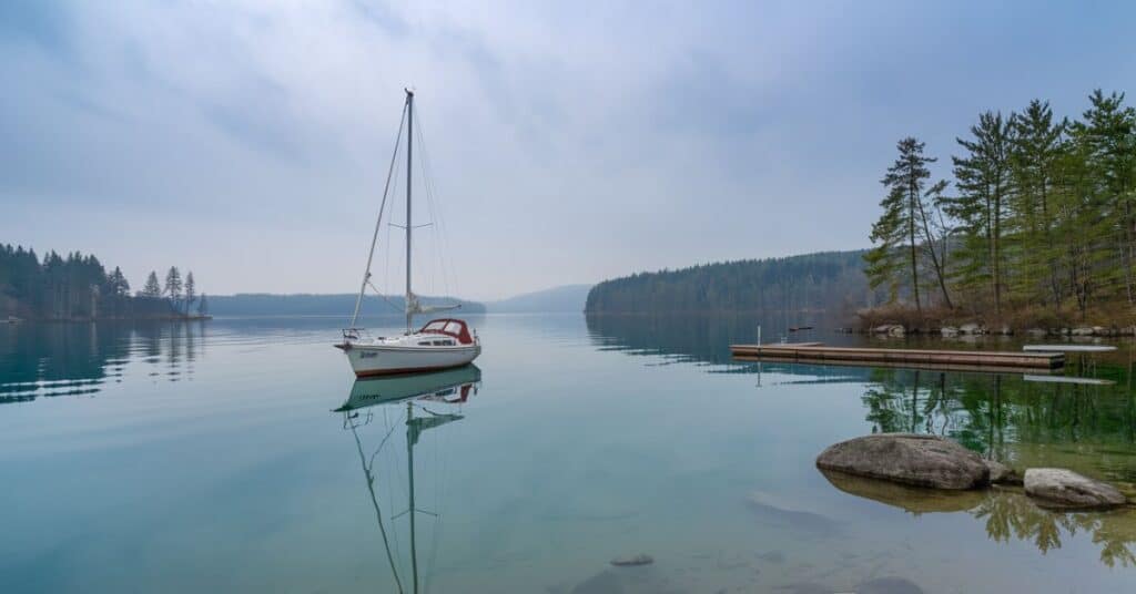 An image of a small sailboat sailing on a calm lake, demonstrating its suitability for beginners.