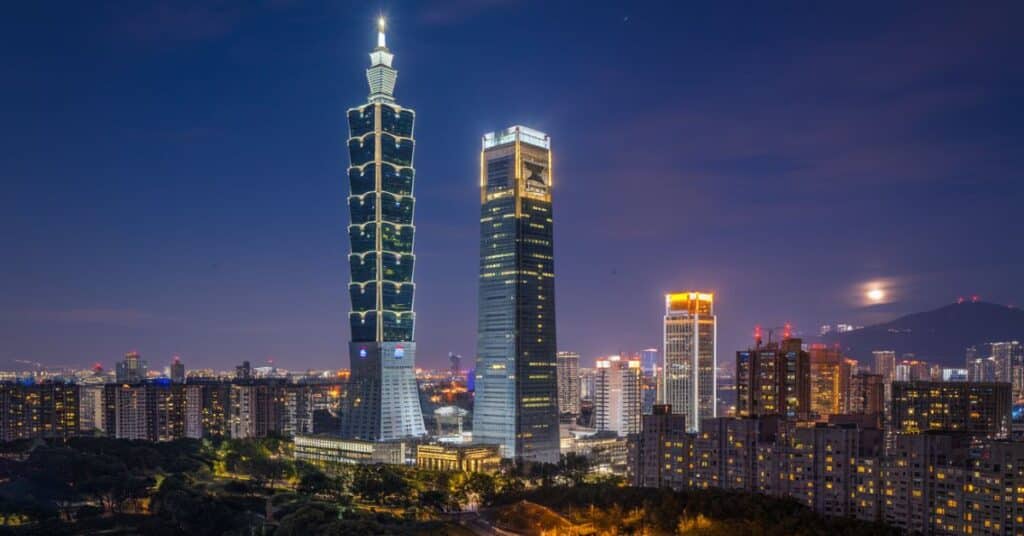 A night shot of Taipei 101 lit up, showcasing its unique architectural features.