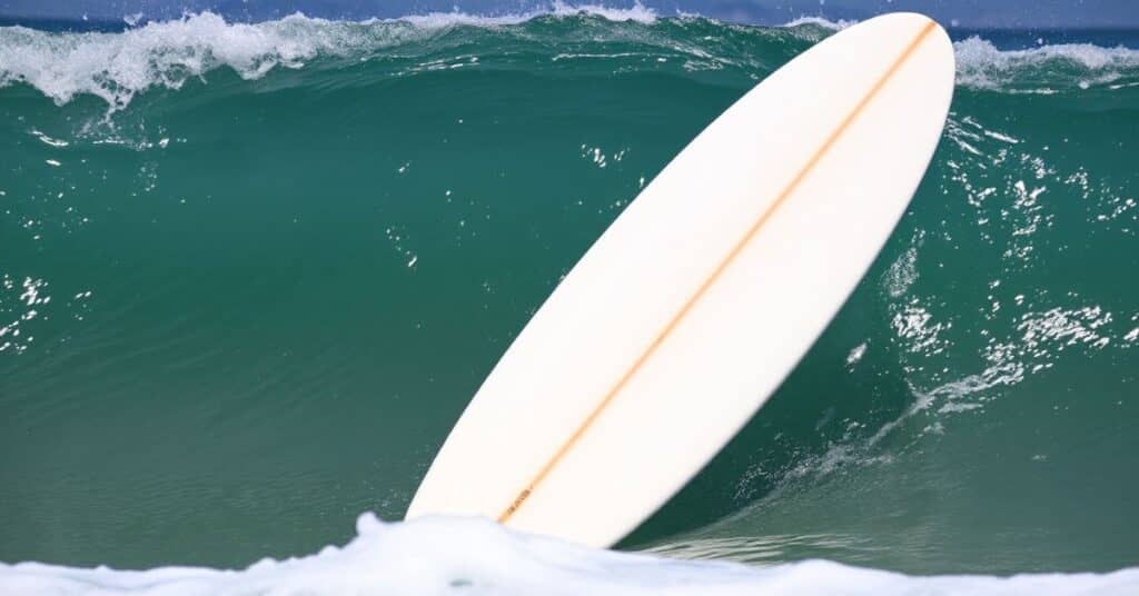 A white surfboard with orange strip in the middle of it. The background is the beautiful blue ocean.