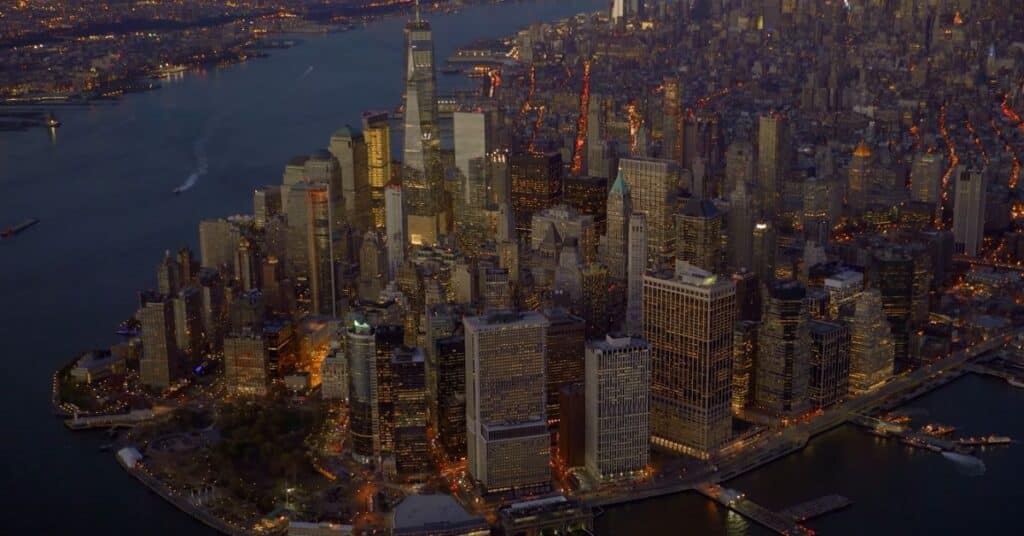 Ariel view of New York City at night. Many of the skycrappers are showing in the picture and all of them are glowing because of the lights.