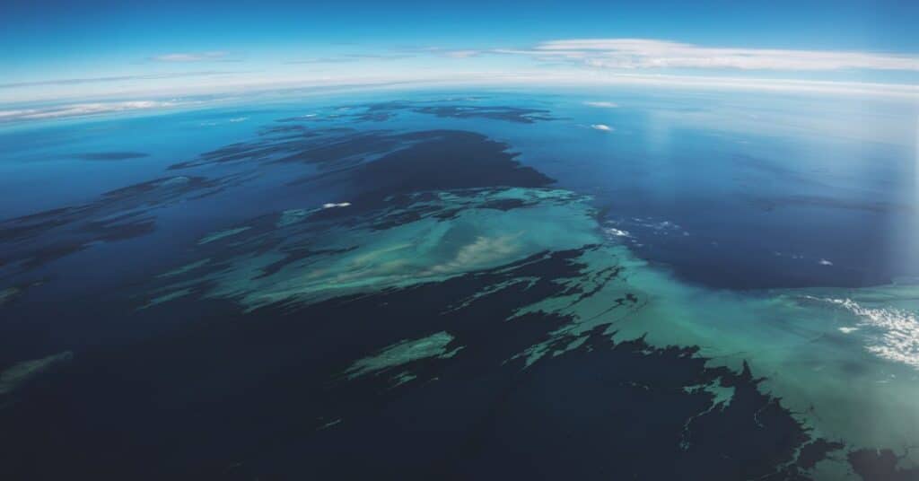 An image of the middle of the Sea. The water is a deep blue, with patches of lighter blue and green, possibly indicating differences in depth or temperature. There are no visible landmasses.