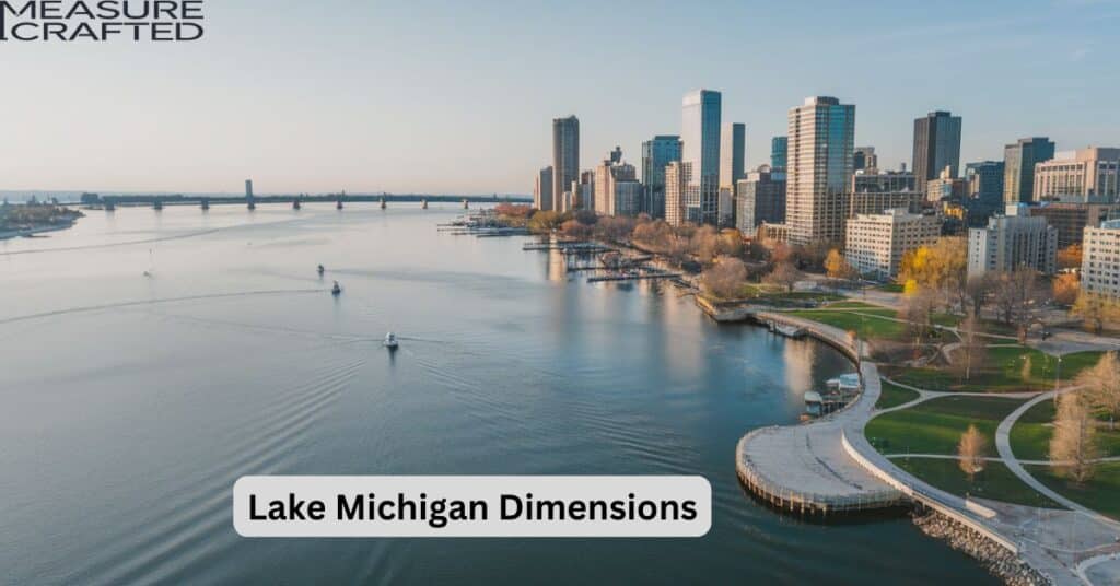 An aerial view of Lake Michigan along the city. The lake is calm with a few boats on the water. The city has tall buildings, parks, and a boardwalk. There are also roads and bridges near the lake. The sky is clear, and the buildings are reflected on the lake.